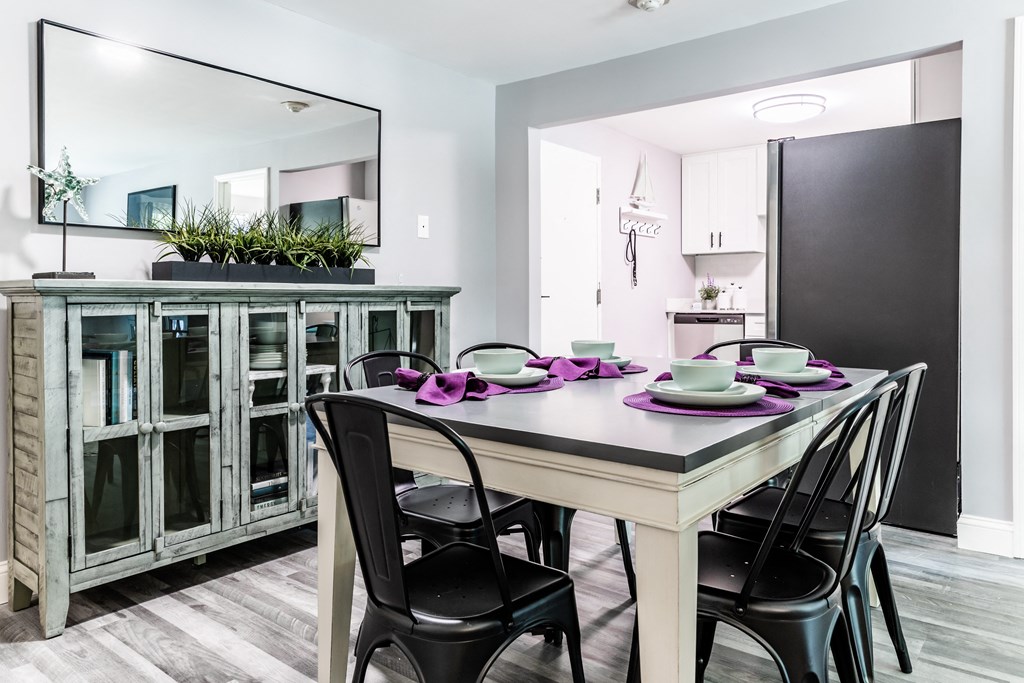 a dining area with a table and chairs and a kitchen in the background