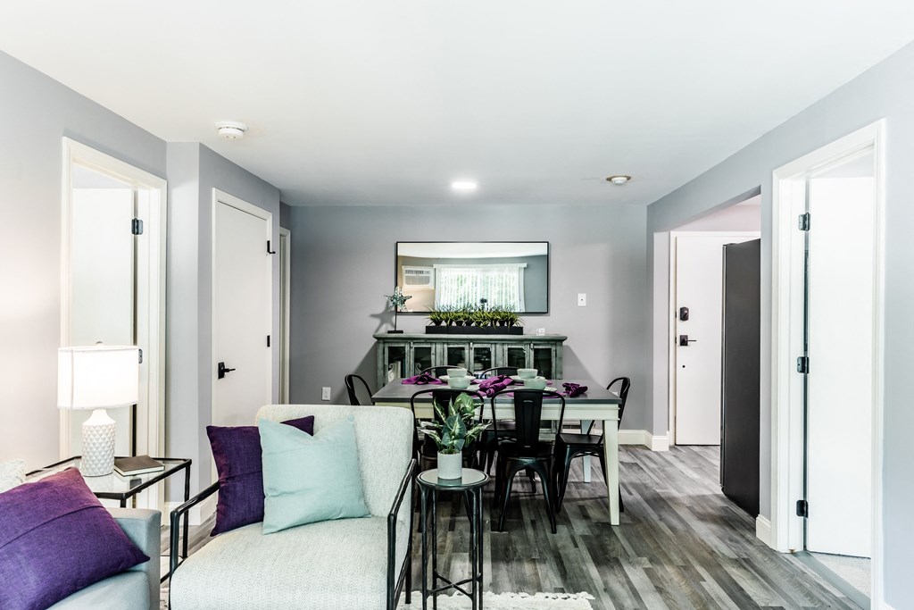 a living room with a couch a table with chairs and a mirror on the wall