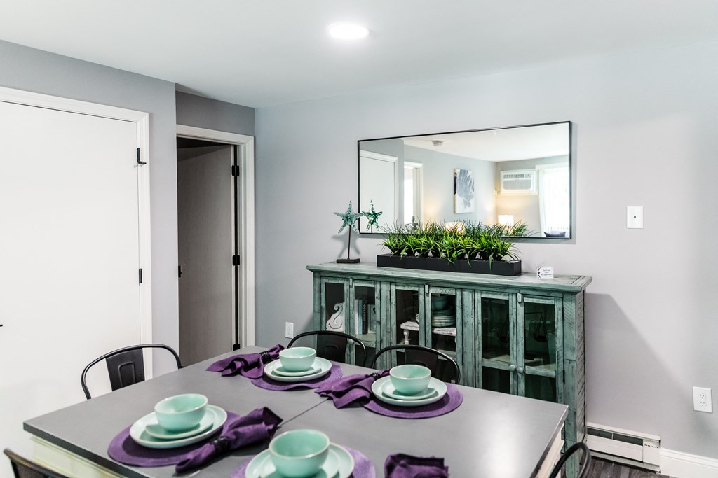 a dining room with a table and chairs and a large mirror