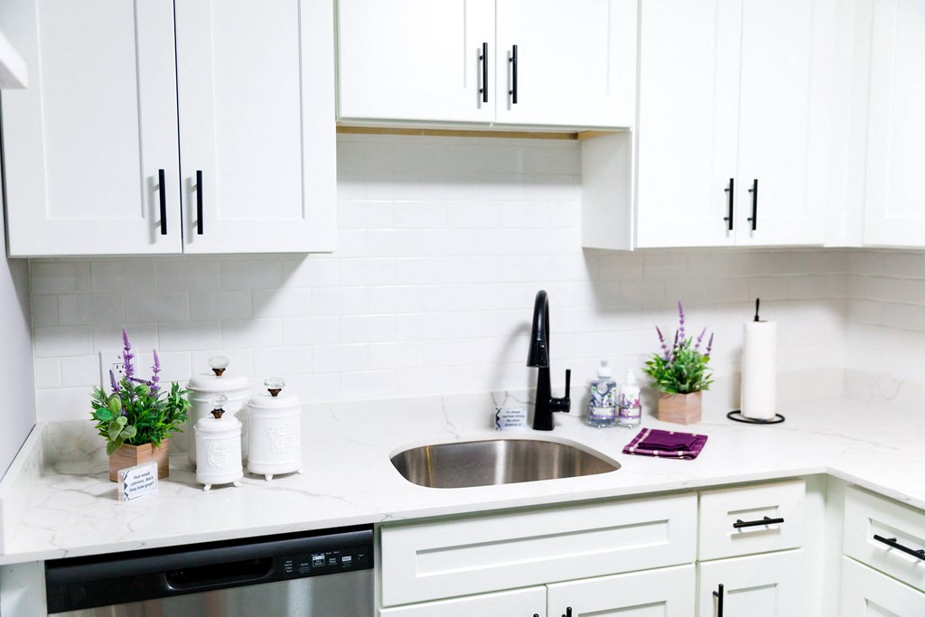 a kitchen with white cabinets and a stainless steel sink