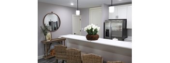 A kitchen with a white countertop and a basket of white flowers.
