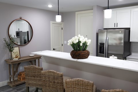 A kitchen with a white countertop and a basket of white flowers.