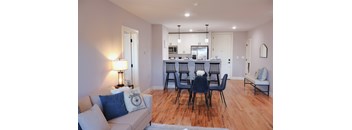 A modern living room with a dining area in the background.