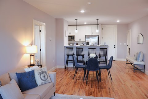 A modern living room with a dining area in the background.