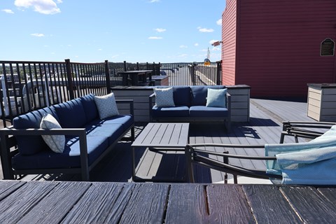 A wooden deck with a blue couch and a white pillow.
