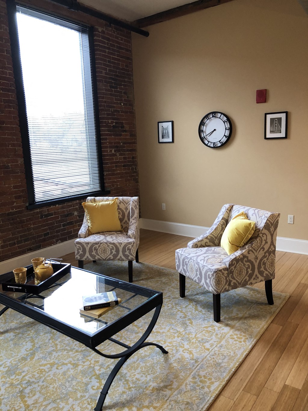 a living room with two chairs and a table and a clock on the wall