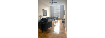 A living room with a black couch and a ceiling fan.