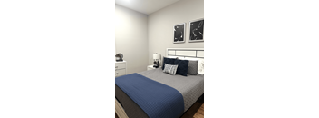 A bed with a blue comforter and pillows in a white room.