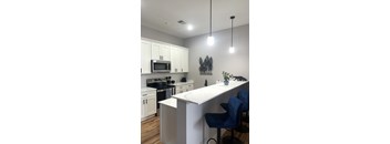 A kitchen with a white counter and blue chairs.