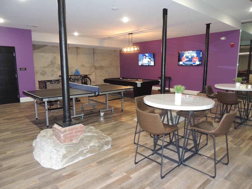 a room with tables and chairs and a pool table and a tv