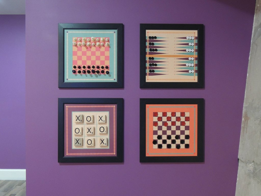 a purple wall with four framed pictures of chess boards on it