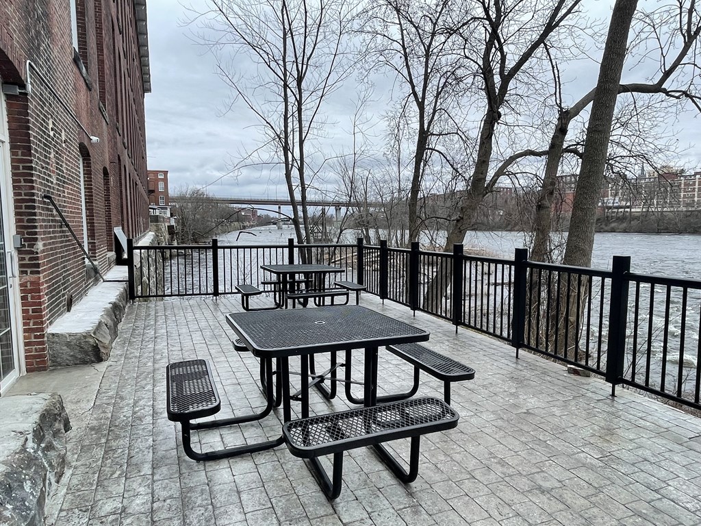 a patio with a table and benches next to a body of water