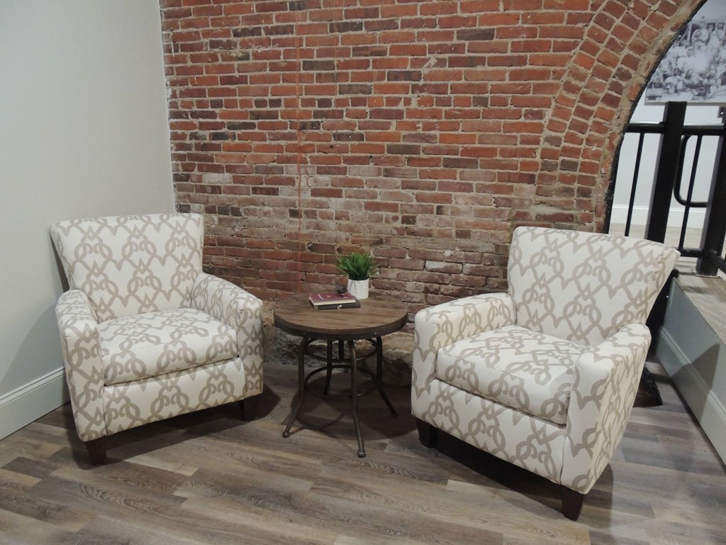two chairs and a table in front of a brick wall