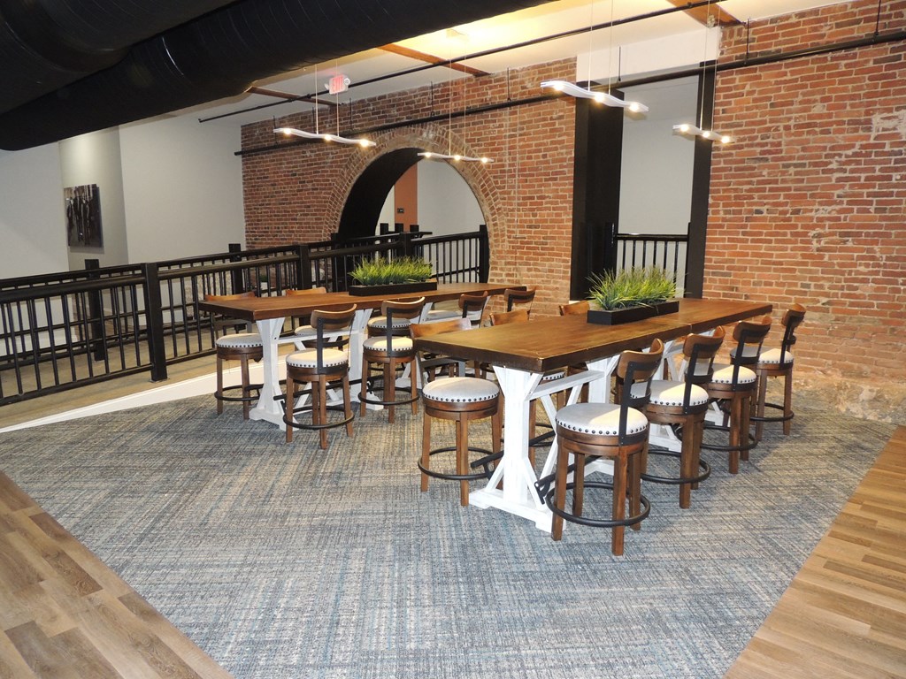 a large dining room with tables and chairs and a brick wall