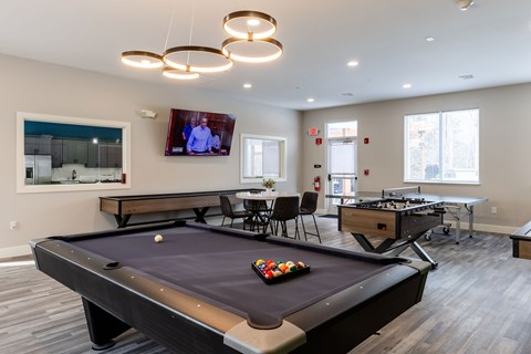A pool table in a room with a television mounted on the wall.
