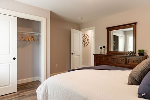 A bedroom with a large bed and a wooden dresser.