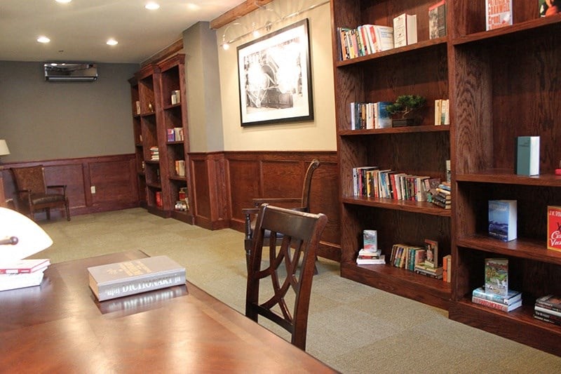 a library with wooden shelves and a table with a chair