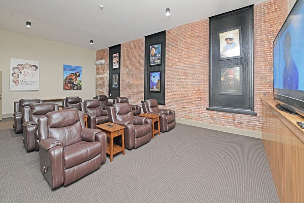 a living room with leather chairs and a brick wall
