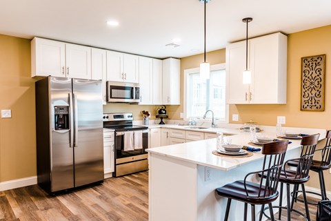 a kitchen with white cabinets and stainless steel appliances and a island with chairs