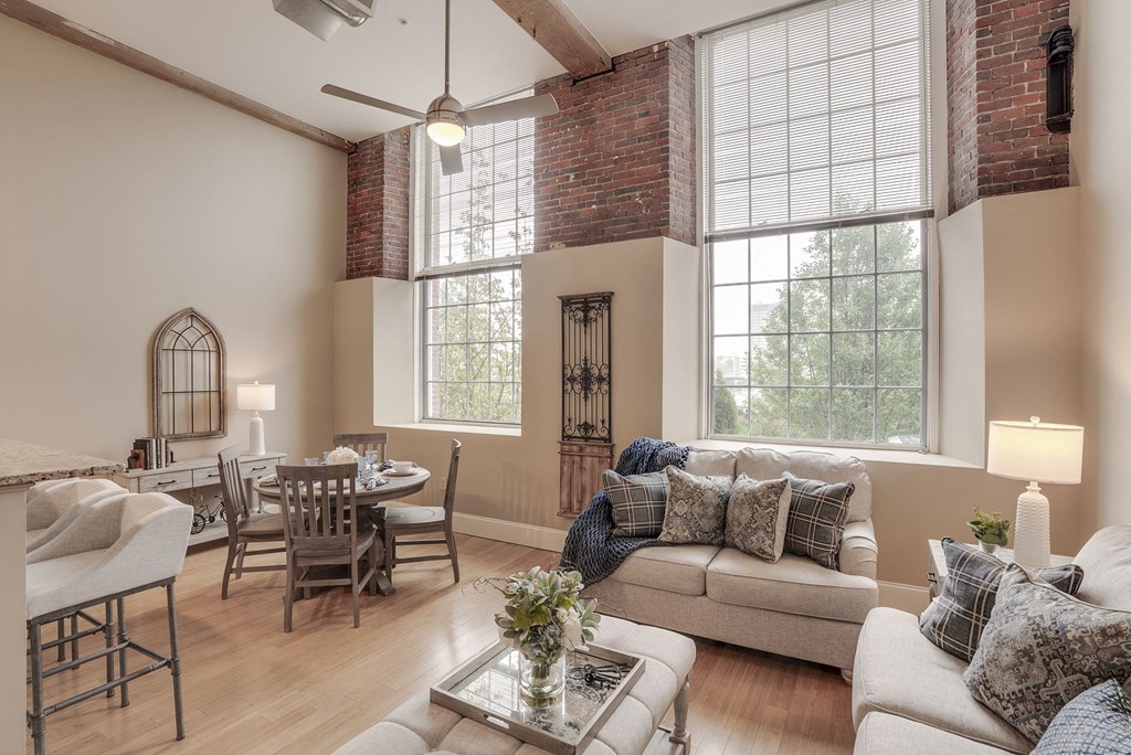 a living room with a couch and a table and a dining room with windows
