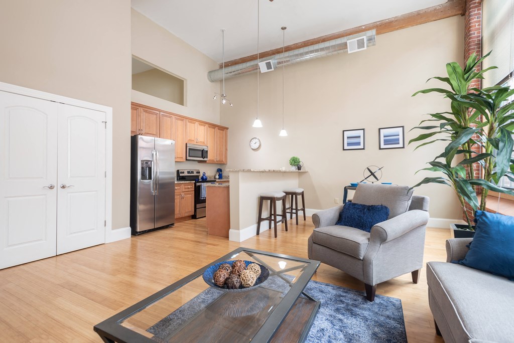 a living room with a couch and a coffee table and a kitchen in the background