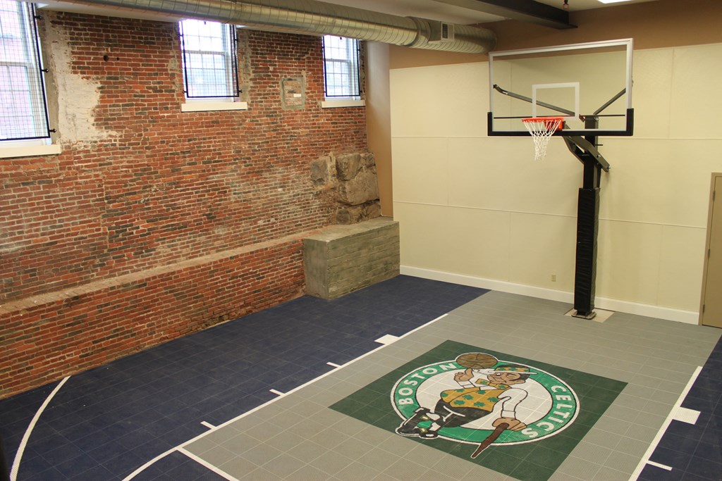 a basketball court with a brick wall and a green and white logo on the floor