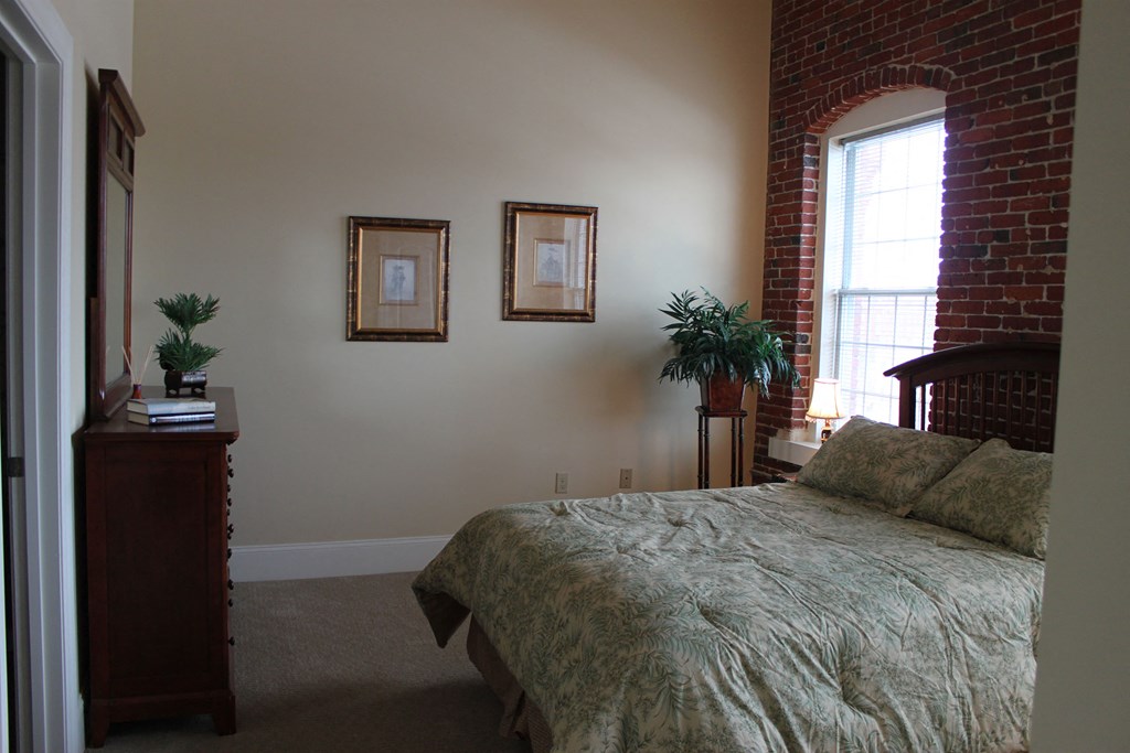 a bedroom with a bed and a brick wall