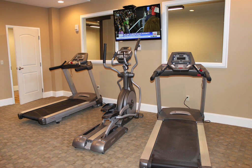 two treadmills in a gym with a tv on the wall