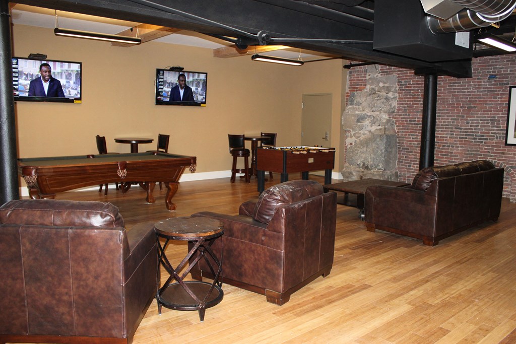 a game room with couches a pool table and televisions