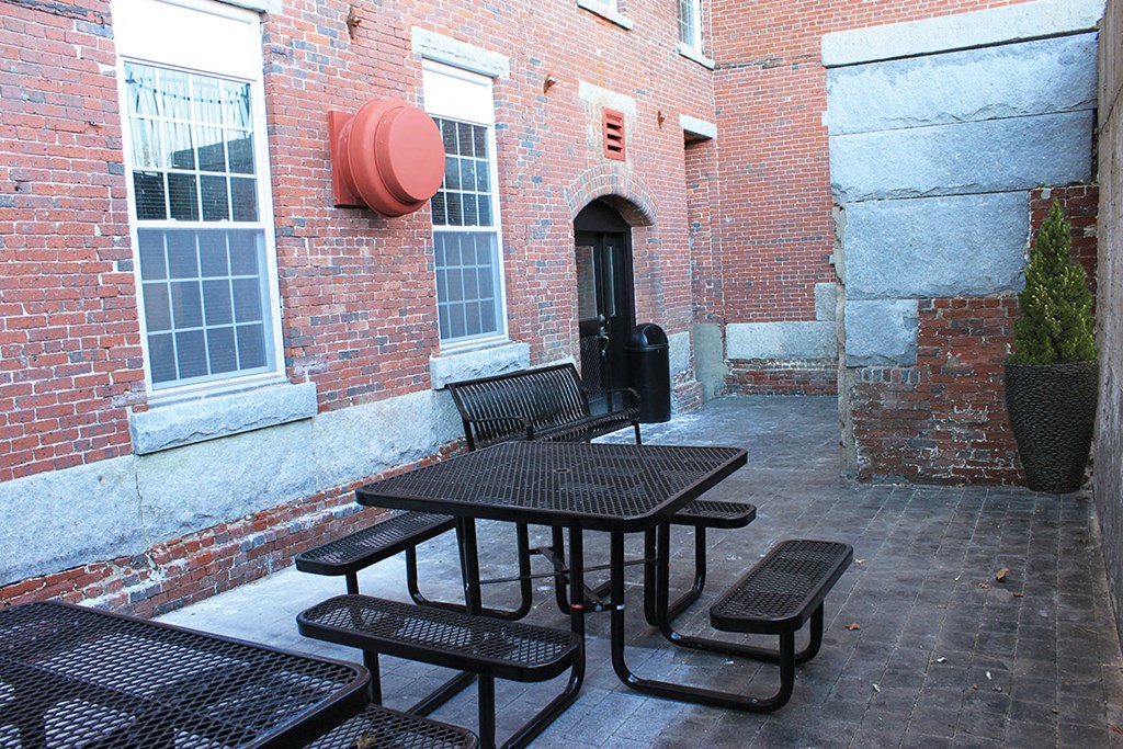 a group of tables and chairs outside of a brick building