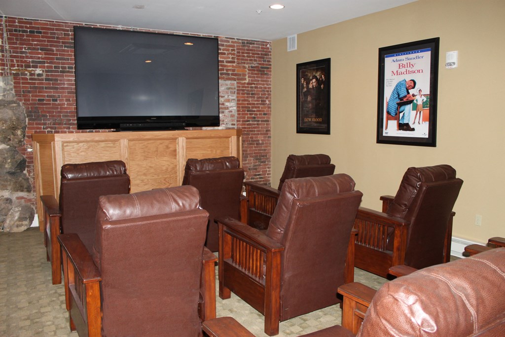 a living room with leather chairs and a television