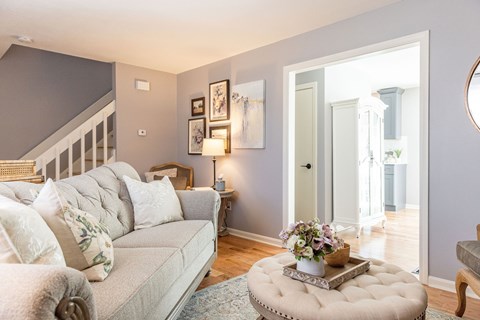 A living room with a grey couch and a round ottoman.