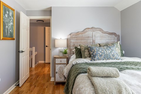 A bedroom with a large bed and a wooden nightstand.