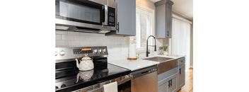 A modern kitchen with a black stove top and a black microwave above it.