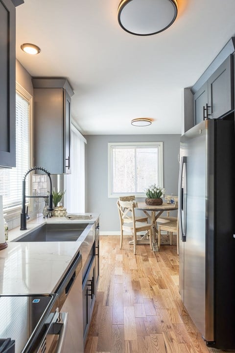 A modern kitchen with a black refrigerator and wooden floors.