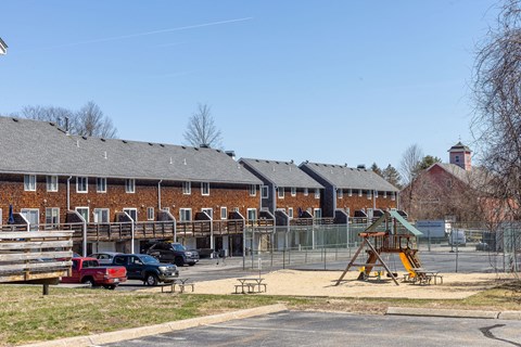 A playground with a slide and a building in the background.