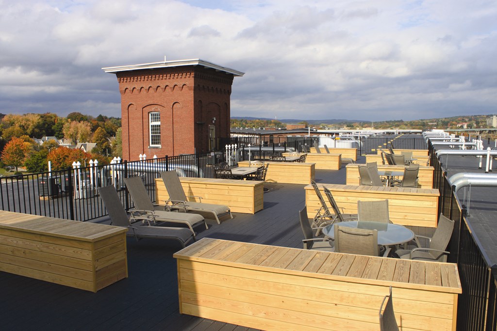 a rooftop deck with tables and chairs and a brick tower