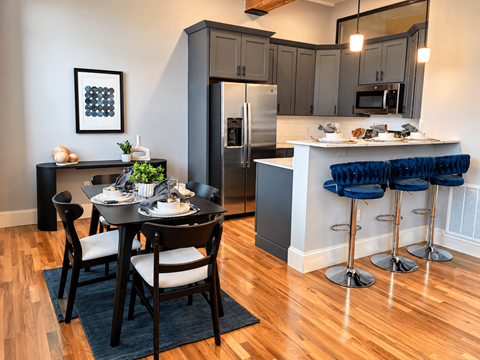 A kitchen with a table set for two and a refrigerator.