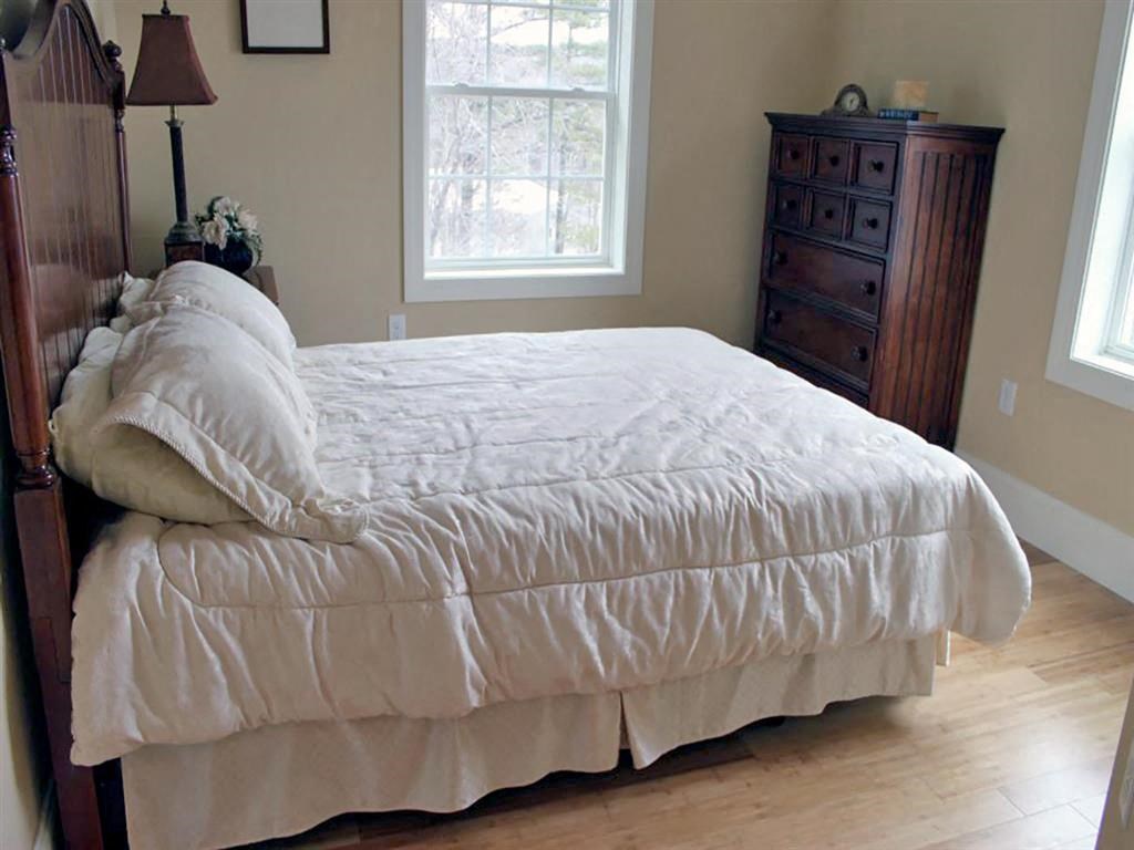 a bed in a bedroom with a white comforter on it