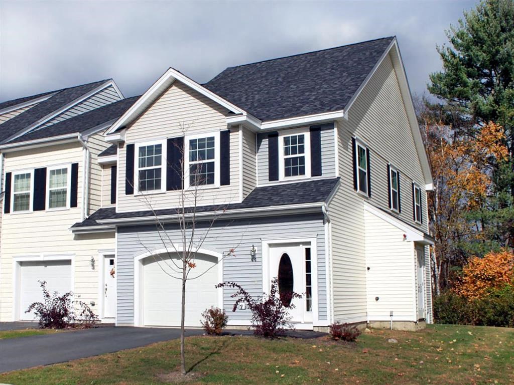 a white house with a black roof and a driveway