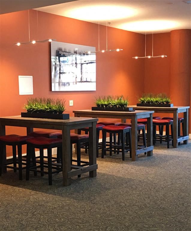 A long table with red chairs and a painting on the wall.