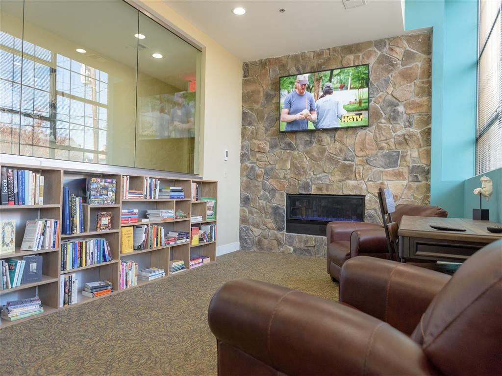 A living room with a stone fireplace and a television playing a movie.