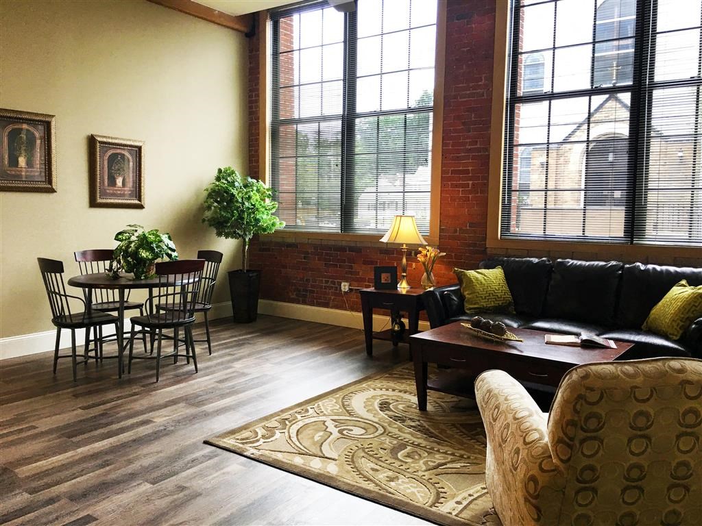 A living room with a black couch and a wooden floor.