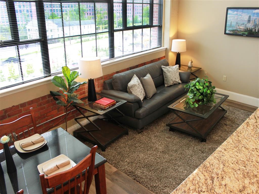A living room with a grey couch, a glass coffee table, and a dining table with chairs.