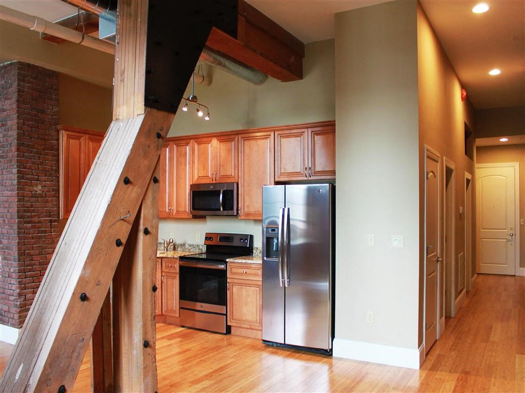 a kitchen with a stainless steel refrigerator and a staircase