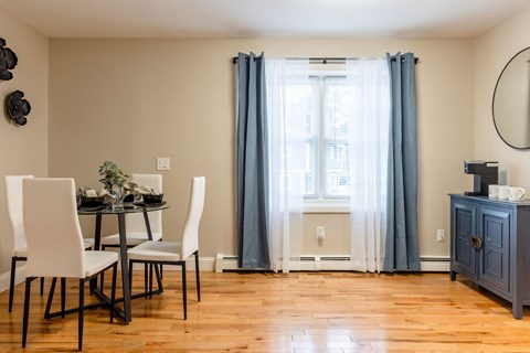 A dining room with a table set for two and a window with curtains.