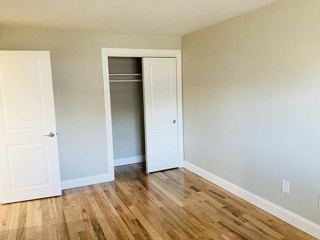 a bedroom with a closet and a hard wood floor