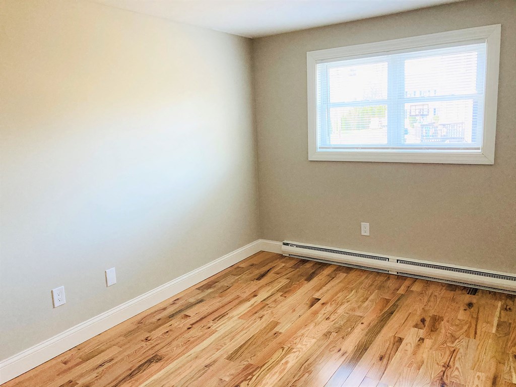 an empty room with wood floors and a window