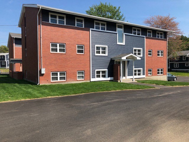 a brick apartment building with a blue roof and a driveway