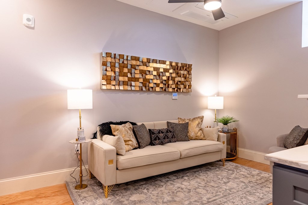 A living room with a white couch and a wooden wall art.